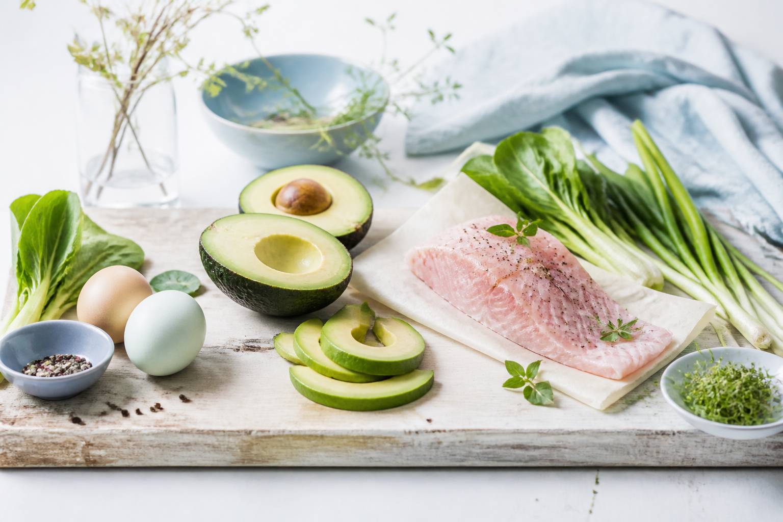 Aliments du régime cétogène disposés sur une table : avocats, œufs, poisson et légumes verts