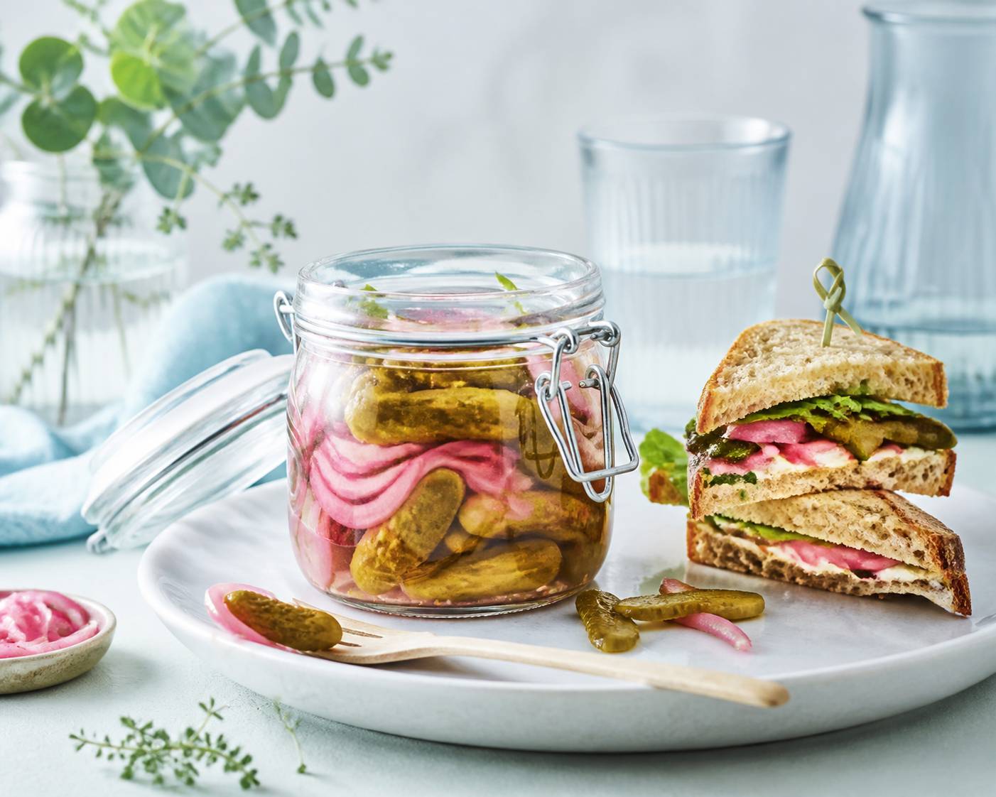 Bocal ouvert de pickles avec un sandwich garni de lamelles