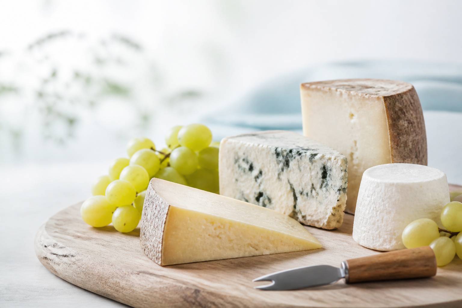 Gros plan de fromages affinés sur planche en bois avec couteau et raisins
