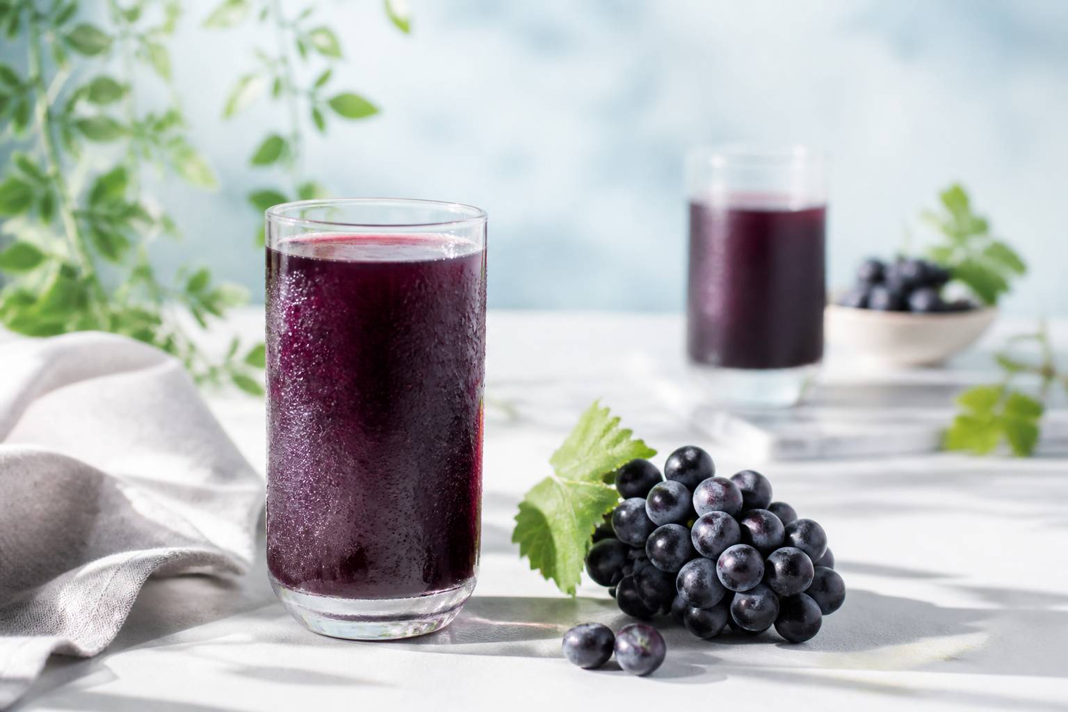 Verre de jus de raisin pourpre avec une grappe de raisin noir au petit-déjeuner