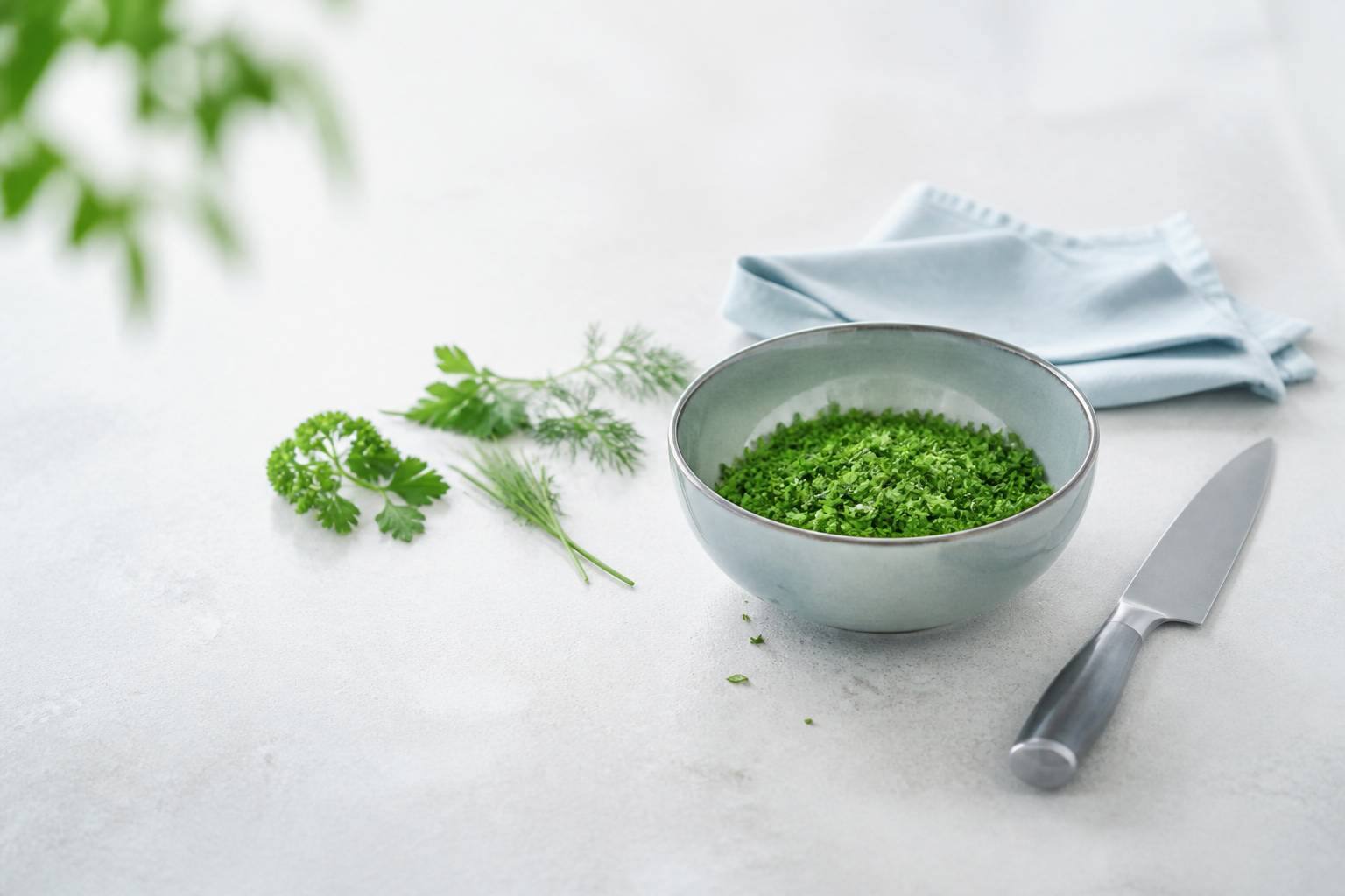 Persil plat et frisé haché dans un bol avec des herbes fraîches sur un plan de travail clair