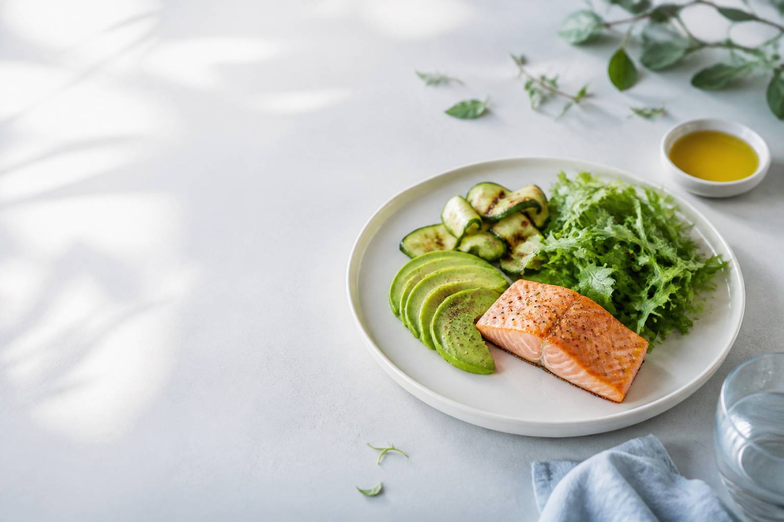Assiette cétogène avec du saumon grillé, des tranches d'avocat et des légumes verts