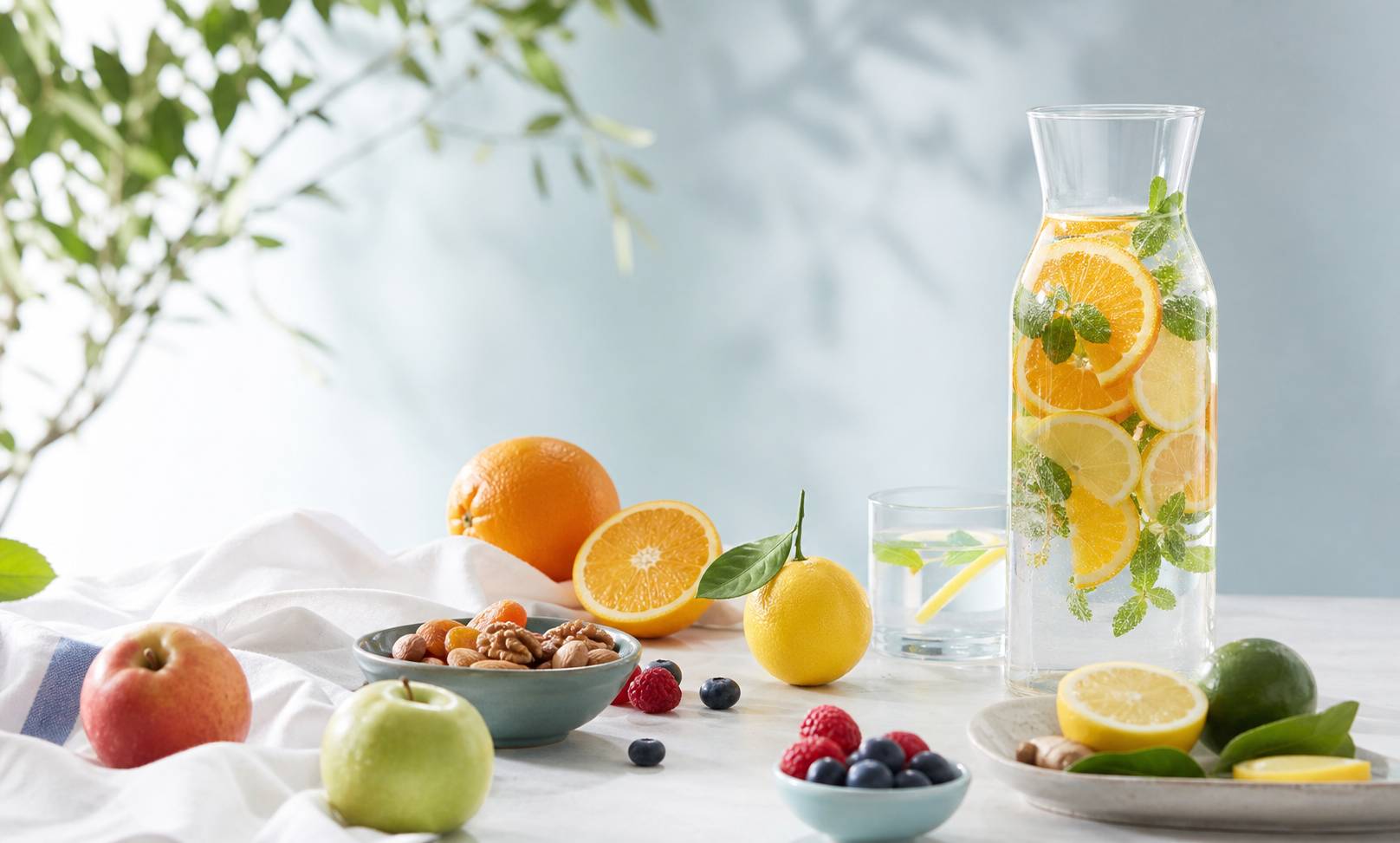 Table lumineuse avec fruits frais, carafe d'eau infusée aux agrumes et bol de fruits secs