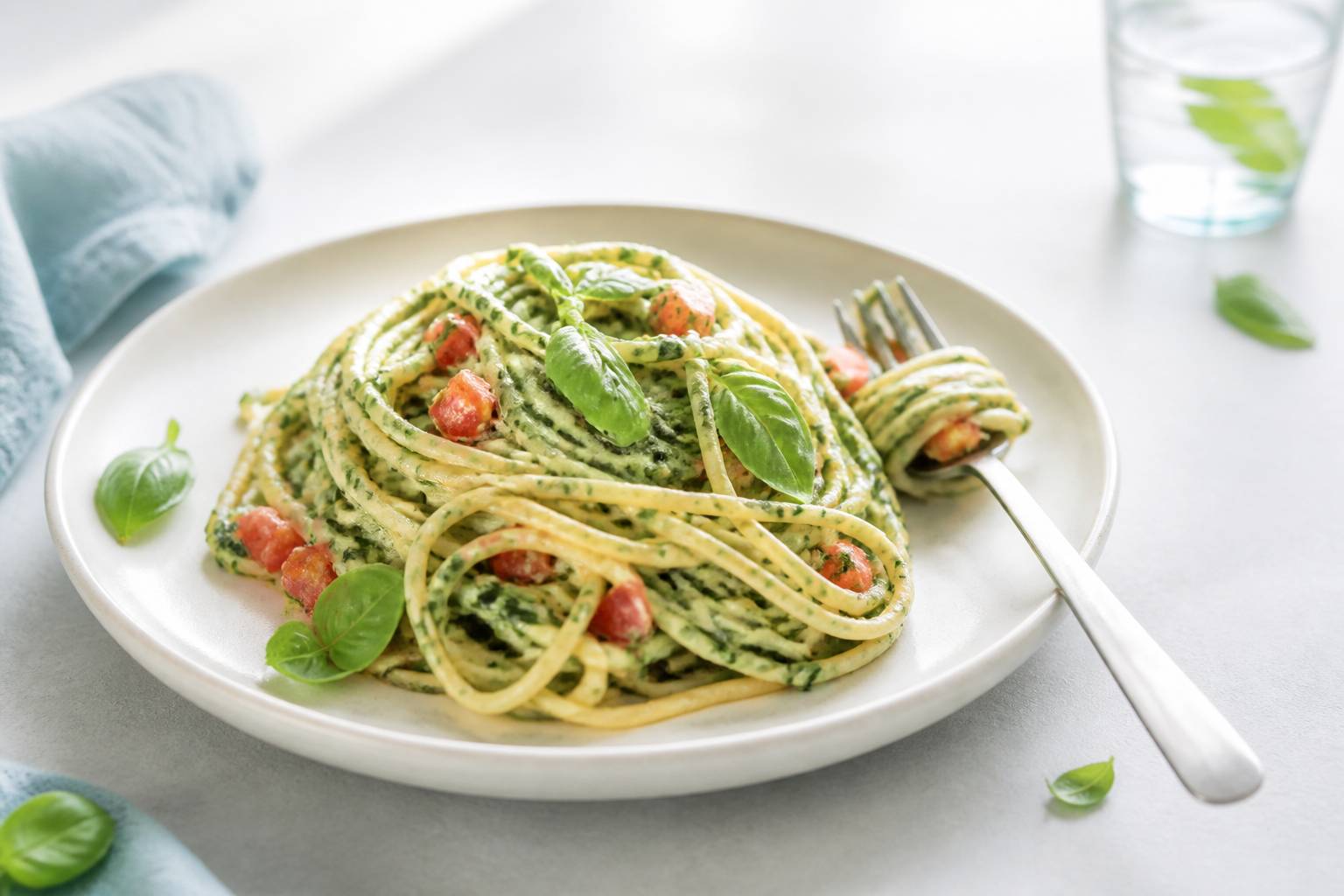 Assiette de spaghettis au blé complet avec sauce verte aux épinards et tomates